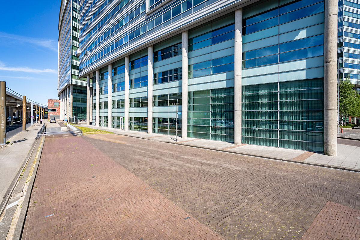 Ansicht der Glasfassade des Bright Offices Amsterdam entlang einer gepflasterten Straße